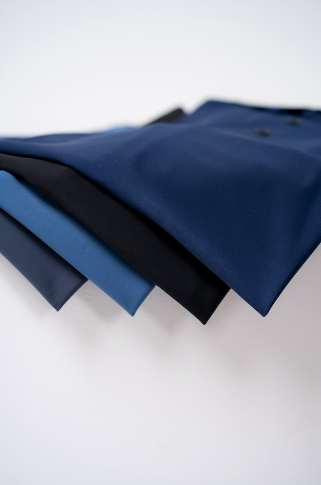 A close up of the Vitali, a high performance polo in navy black and cool blue made out of stretchy shape retention fabric.